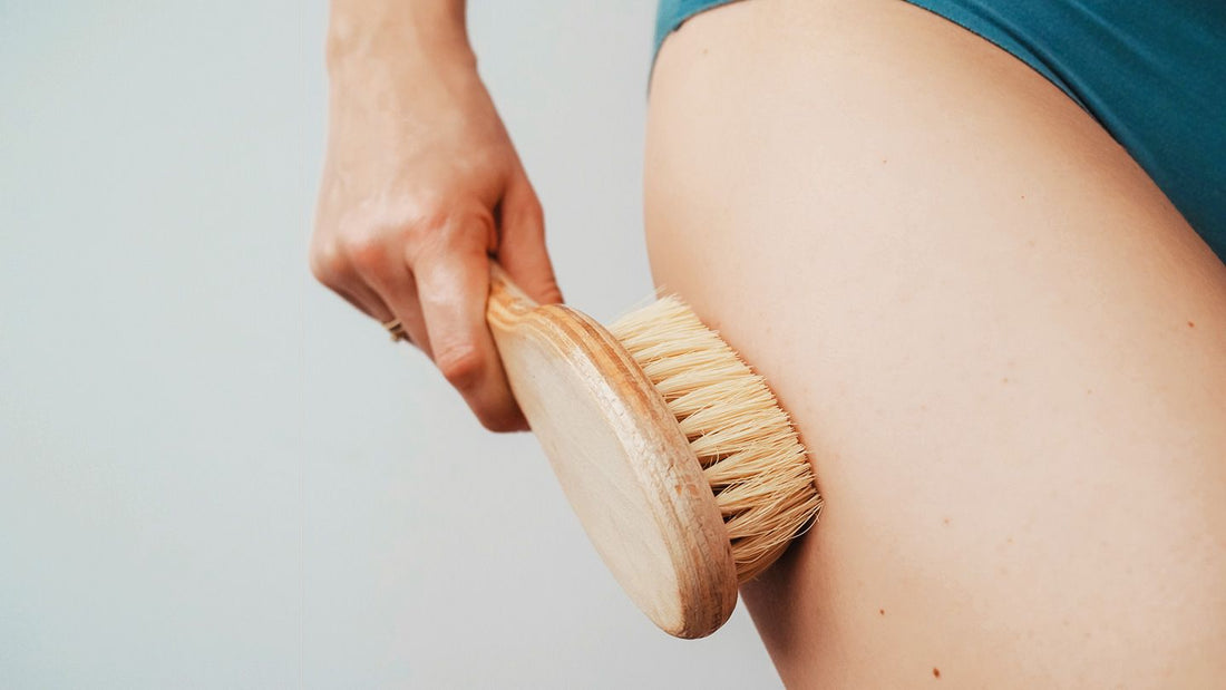 Person using a hard bristle wooden dry brush on their upper thigh